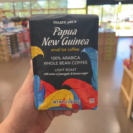 Trader Joe's Papua New Guinea Small Lot Coffee — third front view in different store lighting, showing 100% Arabica Whole Bean Coffee, Light Roast, notes of pineapple & brown sugar, net wt 12 oz (340g), Kosher Pareve (KSA)