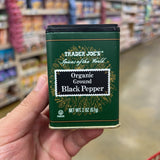 Trader Joe's Spices of the World Organic Ground Black Pepper 2 oz dark green metal tin front, U Pareve, Net Wt. 2 oz 57g, gold botanical illustration, black flip-top lid